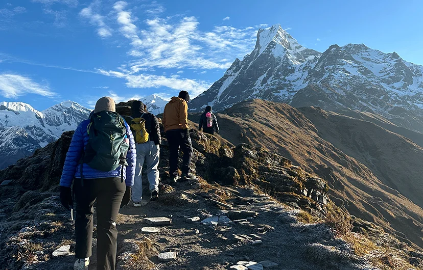 Hikers trekking towards Mardi Himal Base Camp with stunning views of Mt. Machhapuchhare (Fishtail) directly ahead in the Annapurna region of Nepal.